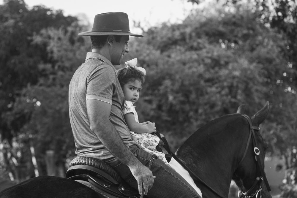 Pai e filha montados a cavalo, em preto e branco