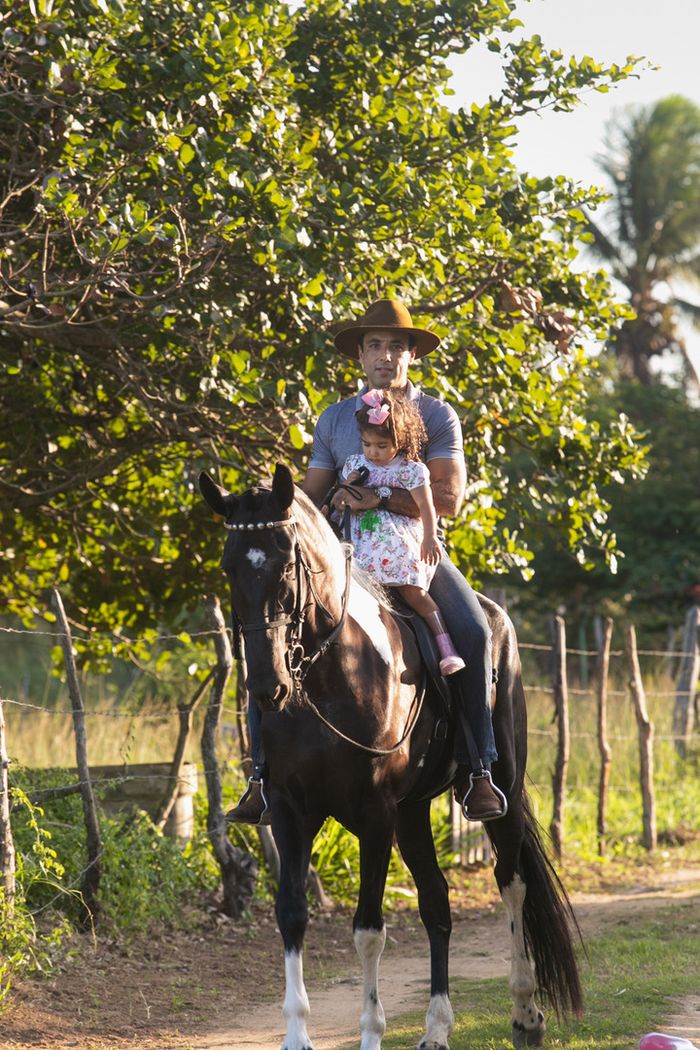 Pai e filha a cavalo na estrada do haras